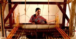 Alt: Indian artisan weaving traditional cotton fabric on a handloom.